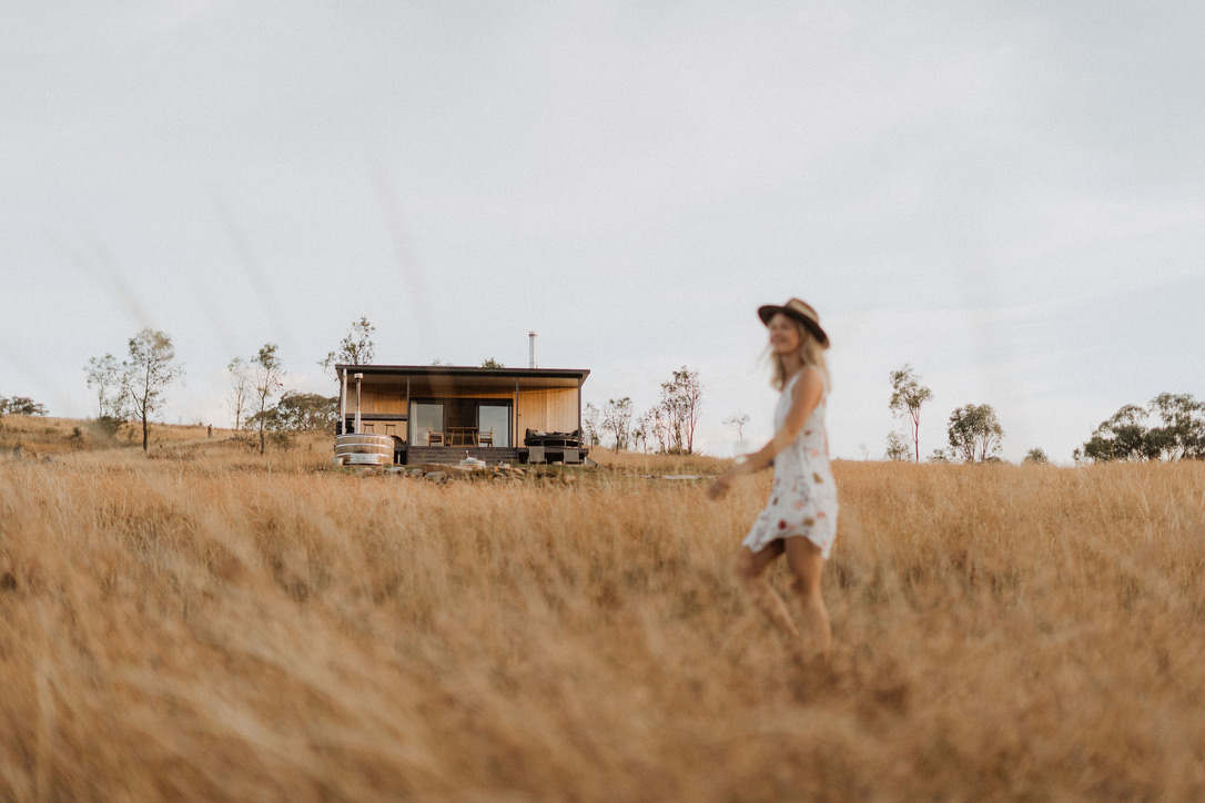 Woman walking in golden field with SIPs cabin behind