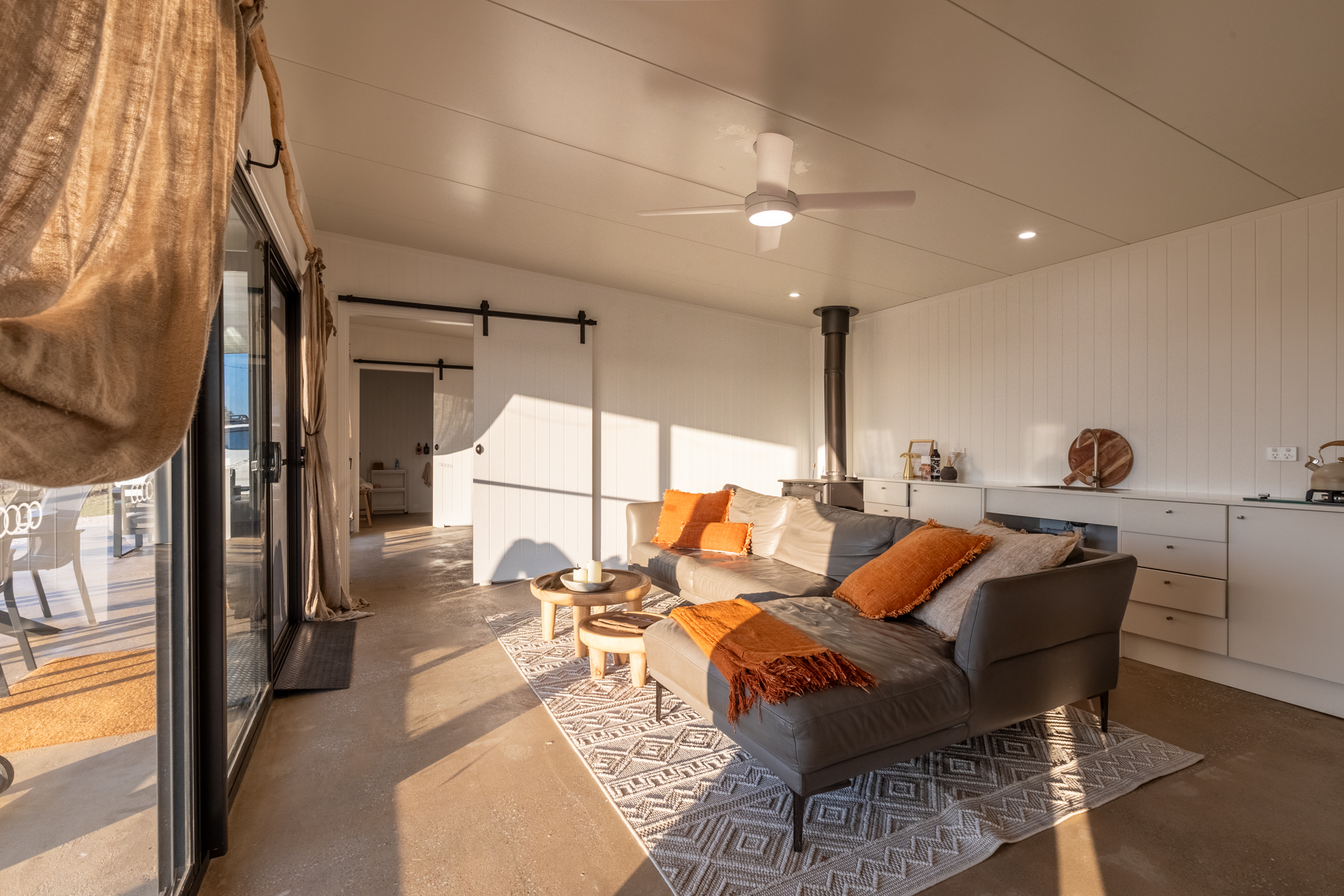 Open-plan living room with wood stove and orange cushions